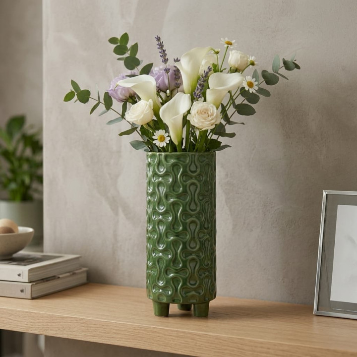 Green ceramic vase with relief and flowers on sideboard